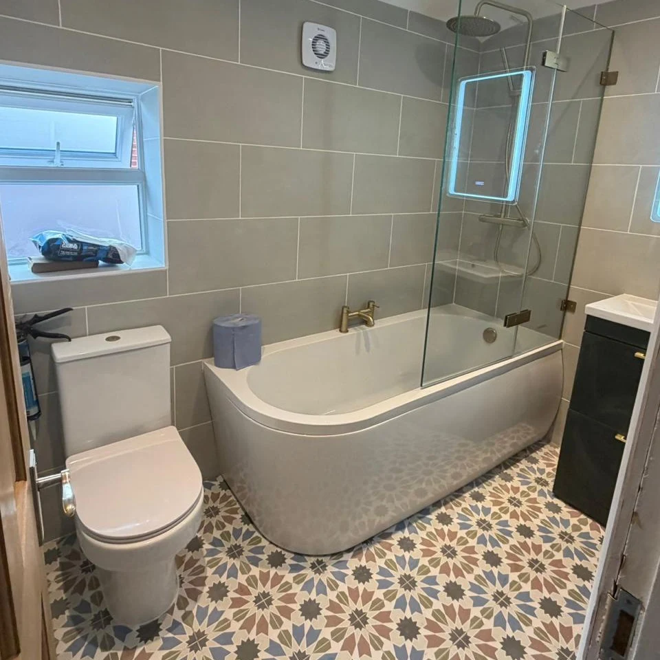 Curved bath and patterned bathroom floor viewed through the doorway — RV Renovation, Oxford